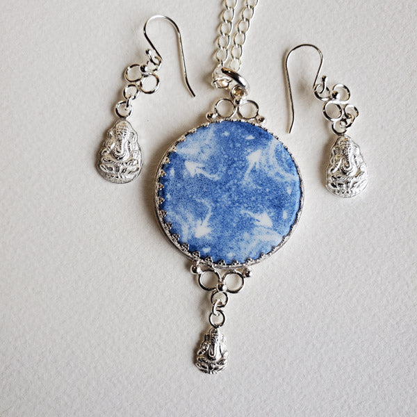 Sterling Silver Earring and Pendant set featuring  a One of a Kind Handmade porcelain  round focal cabochon. This wonderfully unique gift set features the use of the the art form of  Blue Transferware and was inspired by antique shipwrecked tableware shards. Set includes a  Complimentary 22 inch Sterling Silver Chain. Miniature Ganesh charms are here to highlight the cosmic tone and north south east west arrows of the focal cabochon. May Ganesh help remove obstacles in in life and bring you good luck.